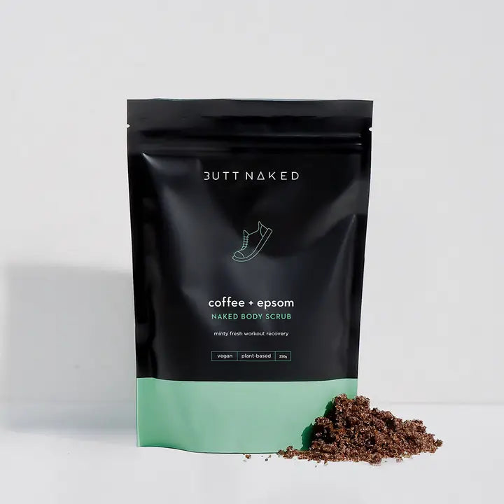 Butt Naked coffee and Epsom Naked Body Scrub packaging with a small amount of scrub on a white background