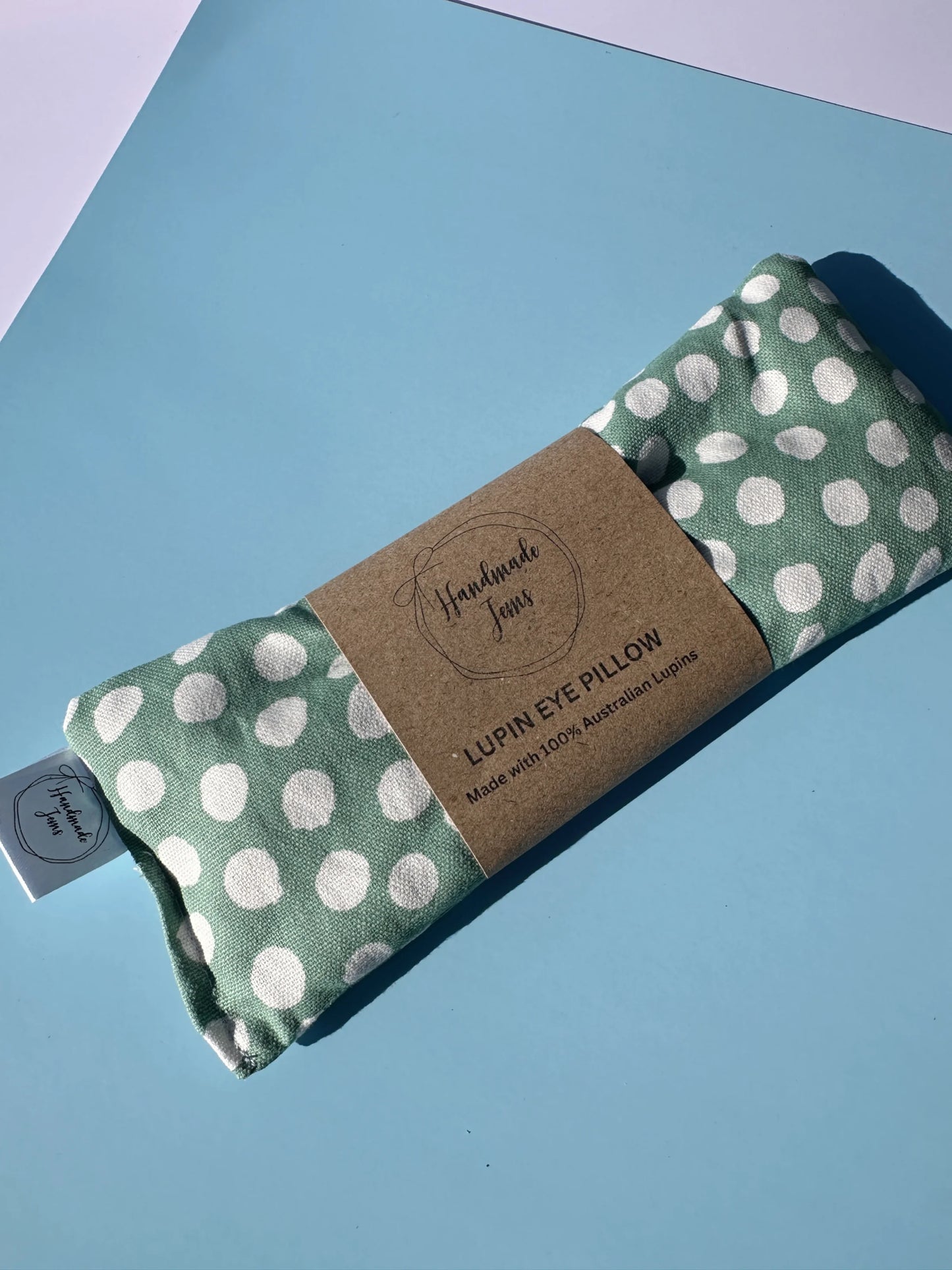 Folded green eye pillow with white polka dots on a blue background