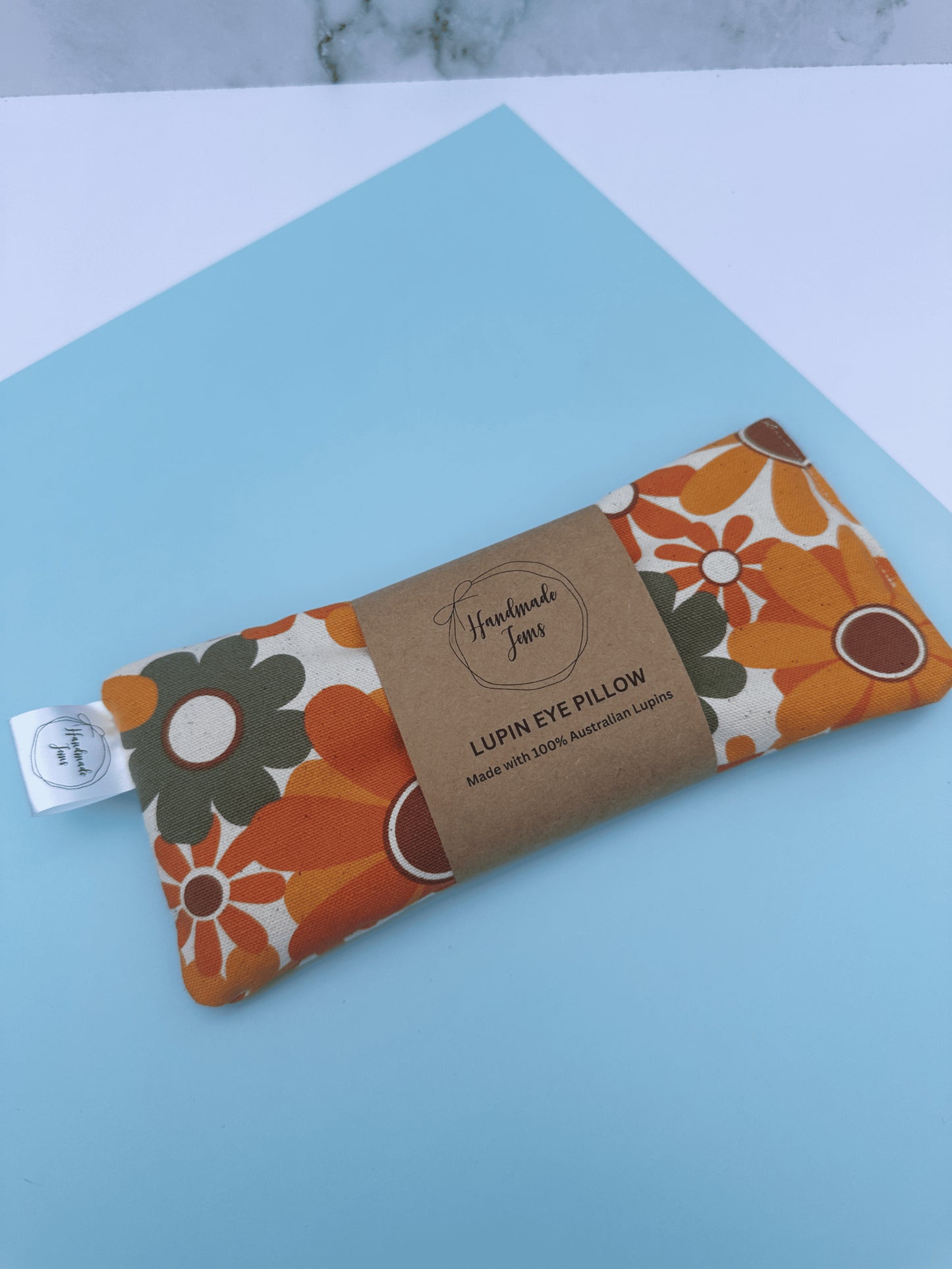 Floral patterned eye pillow with a label on a light blue surface